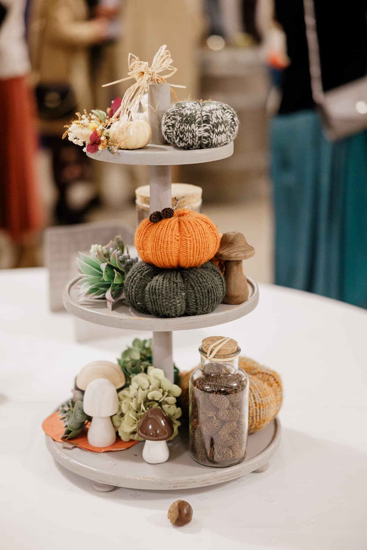 Autumn wedding decor display featuring knitted pumpkins, wooden mushrooms, chestnuts, and pine cones